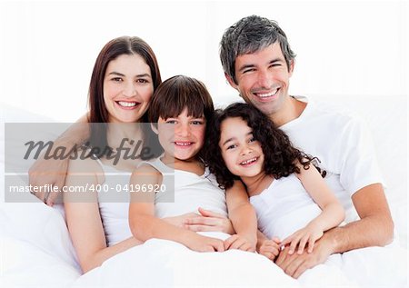 Portrait of a happy family sitting on a bed at home