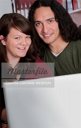 Interracial couple with a laptop at a coffee house with copy space