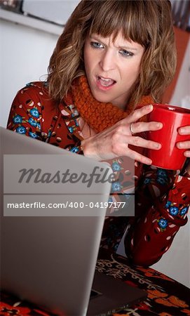 Astonished woman in front of a laptop with drink