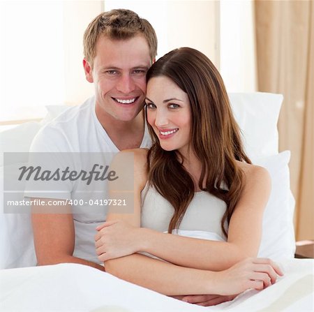 Beautiful lovers embracing lying in bed at home