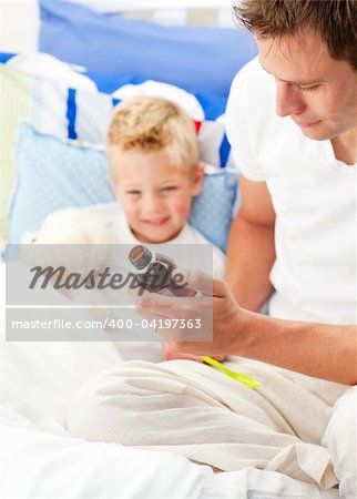 Charming father giving cough syrup to his sick son sitting on bed