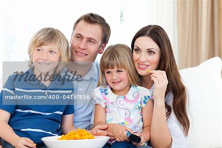 Family watching television and eating chips in the living-room