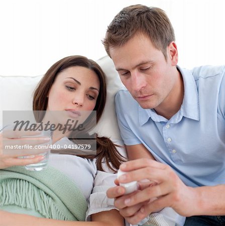 Husband giving pills to his wife with the flu at home