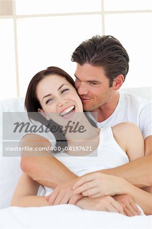 Intimate couple hugging lying in the bed at home