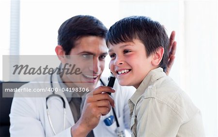 Smiling doctor examining little boy's ears at the practice