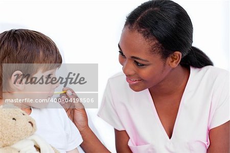 Smiling nurse taking little boy's temperature in a hospital