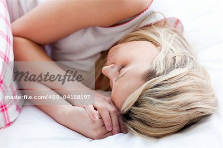 Blond young woman sleeping on a bed at home