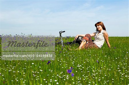 Young woman with a vintage bicycle on a green meadow