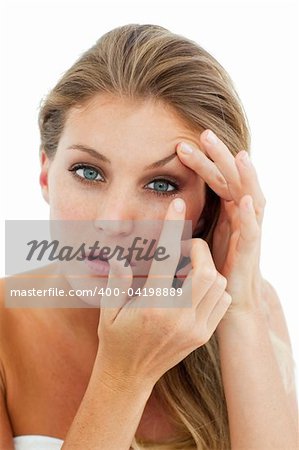 Concentrated woman putting a contact lens isolated on a white background