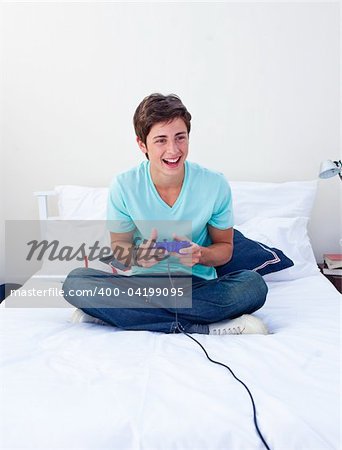 Excited teenager playing video games on his bed