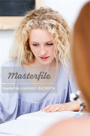 Portrait of a blonde teenager doing homework in a library