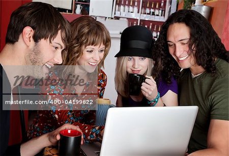 Four friends laughing at content on a laptop