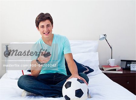 Teen guy watching a football match in television in his bedroom