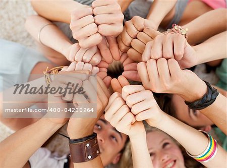 Teenagers lying on the floor with heads together and with thumbs up