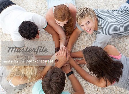 Group of teenagers lying on the floor with hands together