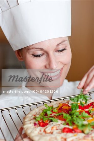 Beautiful female chef preparing a pizza in the kitchen