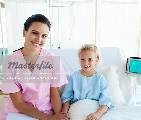 Smiling female doctor with her little patient sitting on a hospital bed