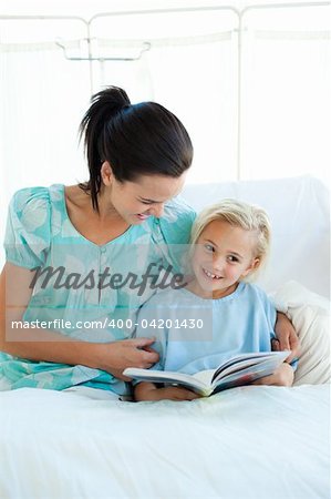 Smiling girl on a hospital bed reading with her mother