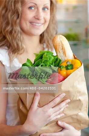 Smiling woman holding a grocery bag in the kitchen