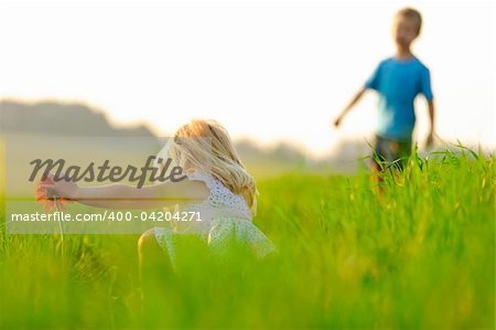 Little girl picks a flower in a meadow, beautiful sunlight lighting.