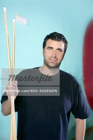 Billiard player man holding two pool sticks over green background