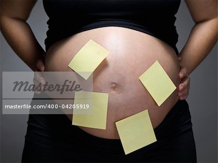 Pregnant woman with blank sticky notes on her belly.