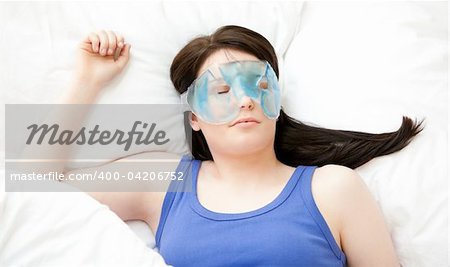 Caucasian young woman sleeping with an eye mask lying on a bed
