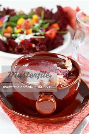 Red cabbage soup with beetroot (borscht) - Russian national dish with vegetable salad in background