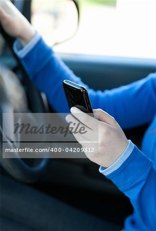 Close-up of a caucasian young woman sending a text while driving in her car
