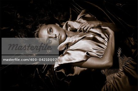 Young girl with long black hair lying poses no iridescent fabric