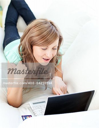 Joyful blond woman looking at her laptop on the sofa at home