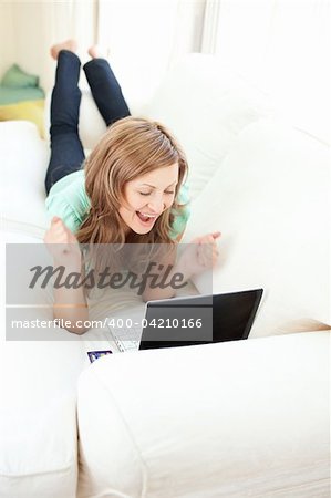 Enthusiastic caucasian woman looking at her laptop on the sofa at home