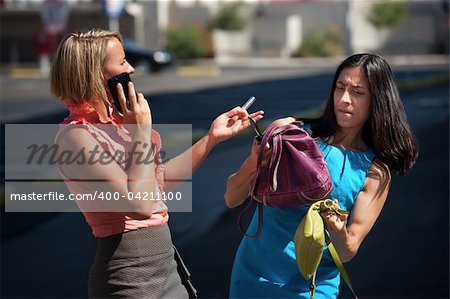 Two friends juggle multiple tasks on city street.