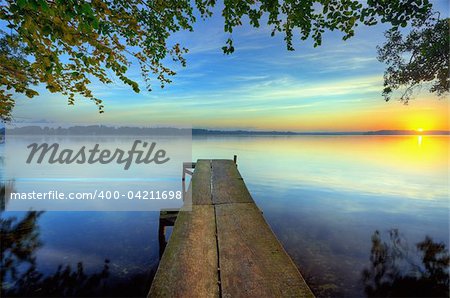 sunrise on a pier with branch hanging out over the water