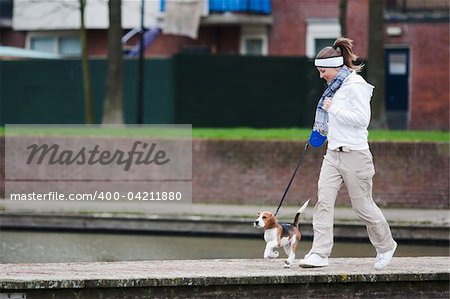 Girl walking with her dog on the leash. Beagle puppy