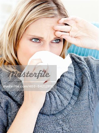 Dejected woman using a tissue sitting on a sofa at home