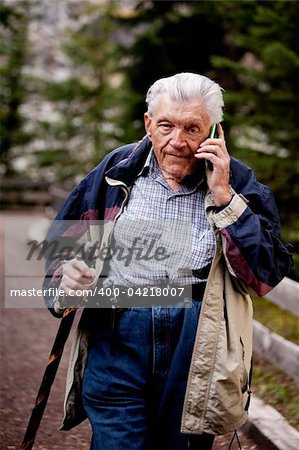 A senior talking on a cell phone outdoors in the forest