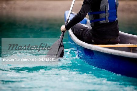 A person paddling a canoe in a turquoise galcier water