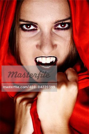 Woman vampire showing her fang and covered in red