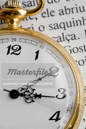 An antique pocket watch with classic numbers and golden casing, on a book.
