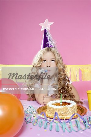 bored little blond girl in a birthday party with cake and candle on pink background