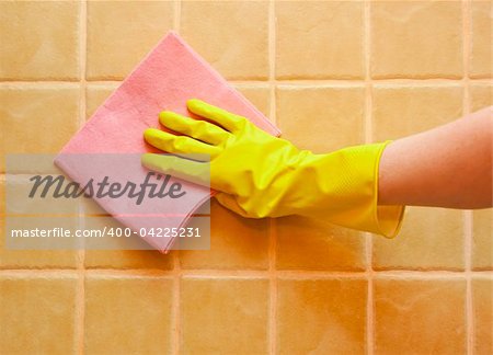 hand in yellow glove with rag, washing tiled wall