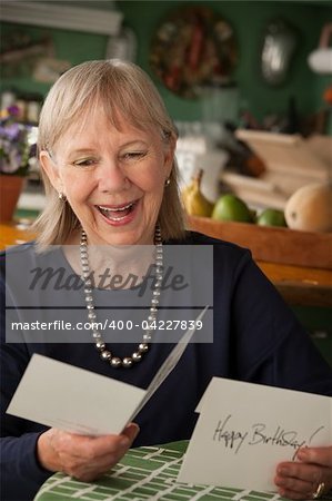Senior woman at home reading greeting card