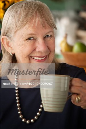 Senior woman at home with coffee or tea