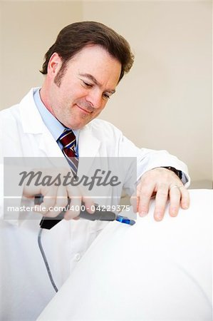 Chiropractor using an electric tool to adjust a patient's spine.