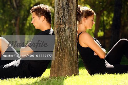 A picture of a young couple sitting in the park and being in a conflict