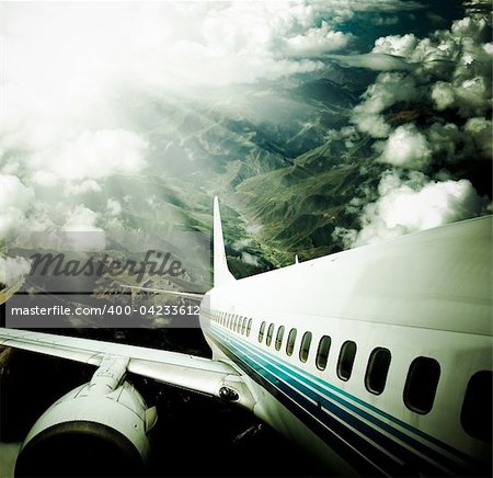 airplane fly above the mountain with clouds.