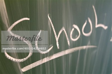 Closeup of the word "school" written on a green blackboard.