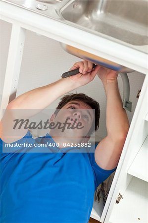 Manual man repairing his sink in the kitchen at home