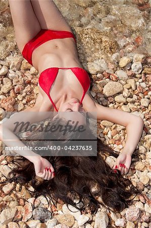 beautiful young woman with beautiful  long hair in a bikini lying on beach